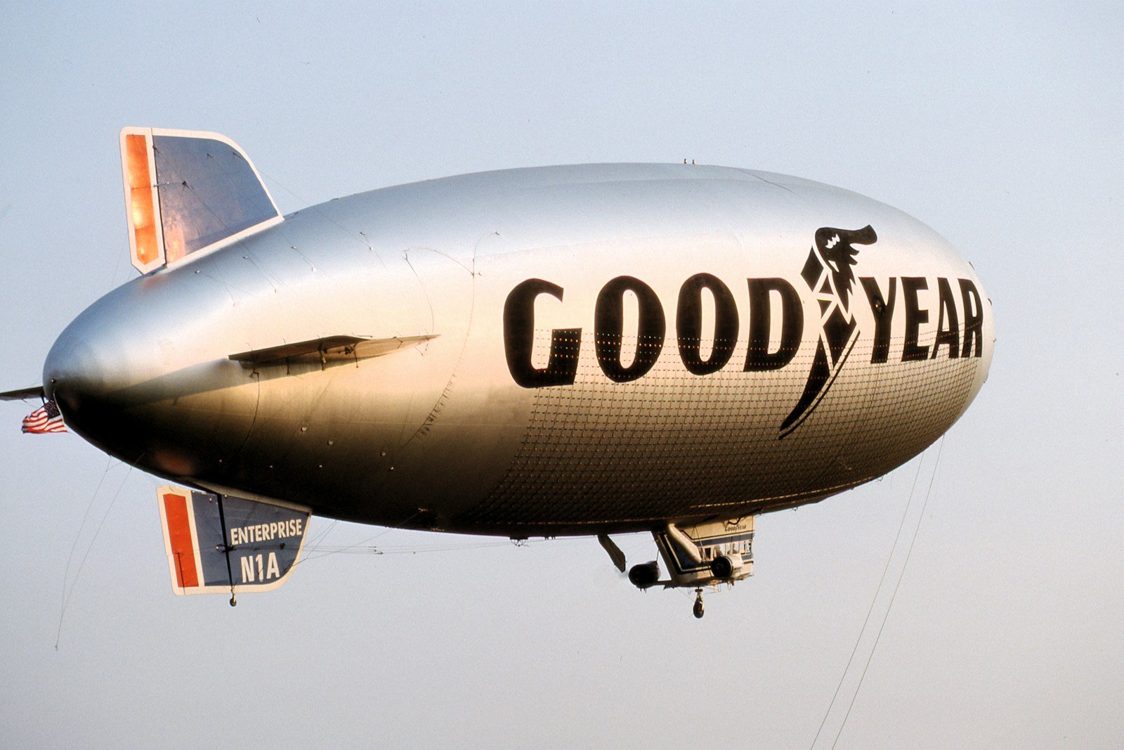 a large silver airplane flying through a blue sky